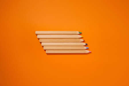 Lots of bright, colored pencils on a orange background full screen.の写真素材