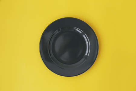 A gray, beautiful plate in the center, on a yellow background, full screen.の写真素材