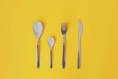 A kitchen spoon lying in the center, on a yellow background, full screen.の写真素材