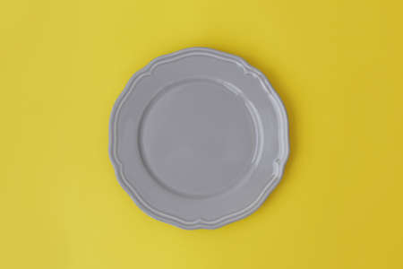 A gray, beautiful plate in the center, on a yellow background, full screen.