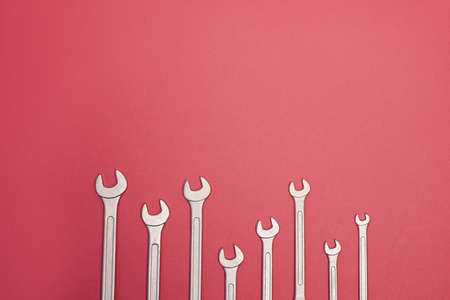 Many steel wrenches on an pink background full screen.