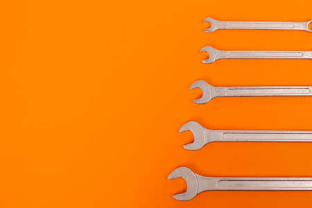 Many steel wrenches on an orange background full screen.