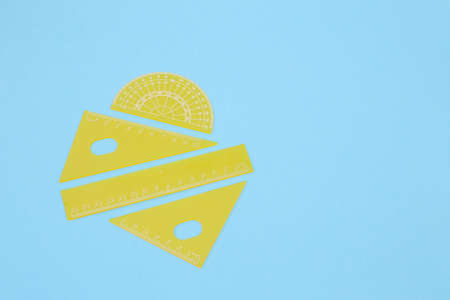 Yellow school rulers on a blue background full screen.の写真素材