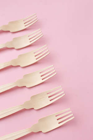 Wooden, eco cutlery on a pink background full screen.