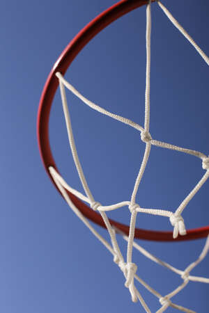 A red basketball hoop with a white net against a blue cloudless sky.の写真素材