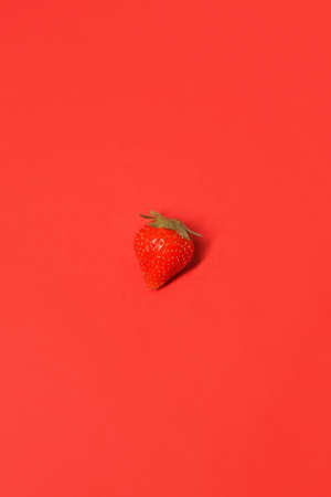 Lots of juicy, red strawberries on a red background in full screen.