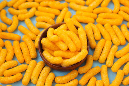 Salty, yellow corn sticks on a bright colored background in full screen.