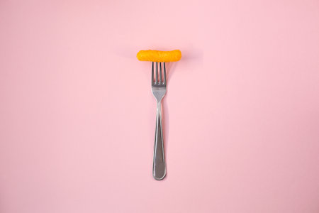 Salty, yellow corn stick on a bright colored background in full screen.