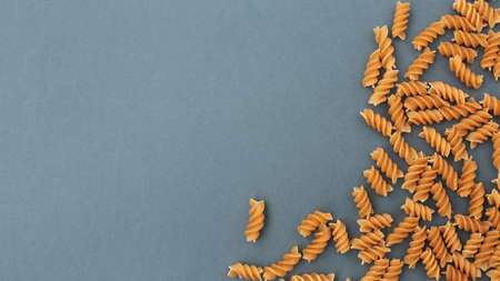 Dry, undercooked, colored pasta on a bright, light, even canvas.の写真素材