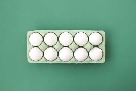 A lot of white chicken eggs on a colorful, even and bright background.