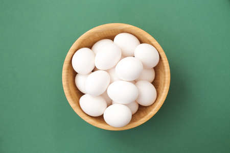 A lot of white chicken eggs on a colorful, even and bright background.