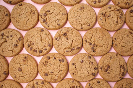 Delicious oatmeal chocolate chip cookies. They lie on an even and colored background.