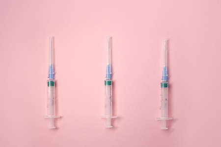 Medical syringes with a needle on a bright pink light background in full screen.の写真素材
