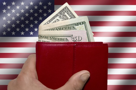 Male hand holding red wallet with US dollar billsの写真素材