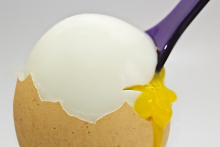 Opened breakfast egg with purple spoon