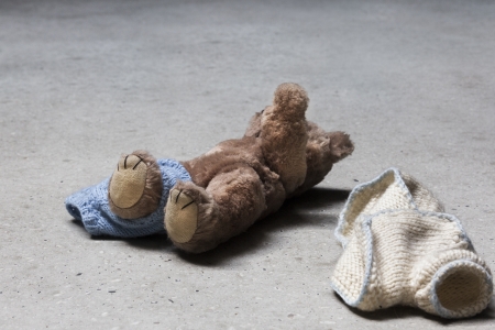 Stripped teddy with raised arm on concrete floorの写真素材
