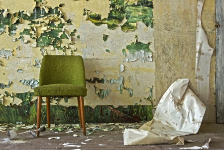 Old chair stands in front of a flaked off wallの写真素材