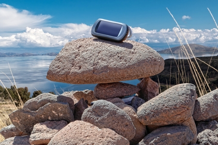 Gps device is placed on stacked rocks of geochache hide.の写真素材