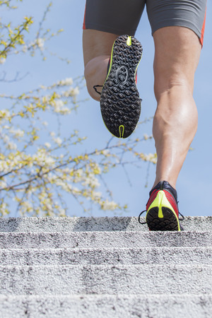 Sportive man runs up the stairs. In the background can be seen the blossoms on the branches  of a...