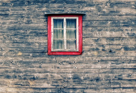 Wooden facade of a mountain hut with an old window and curtains  in the center of the pictureの写真素材