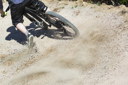 Unfiltered version of mountain bike rider drifting through a gravity slope of an artificial downhill track. Gravel sprays upwards.の写真素材