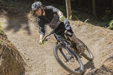Mountain bike rider rides through a gravity slope of an artificial dirt track. The scene is held in earthy colors.の写真素材