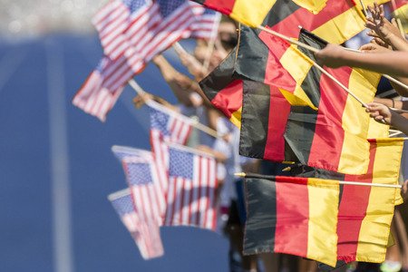 Spectators waving with flags of Germany and USA in front of a blue tartan track. Focus is on the german flags in the foregroundの写真素材