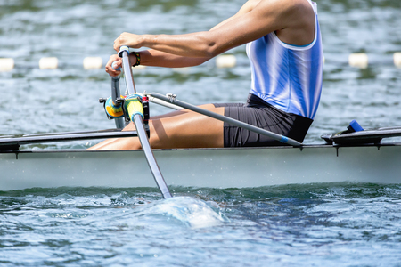 Single rower in a boat strokes the paddle.
