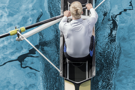 Top view of athletic competition rower, who strokes his  paddle through metallic blue water.の写真素材