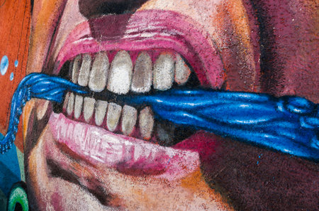 VALPARAISO, CHILE - OCTOBER 29, 2014: Colourful graffiti detail of an aggressive face with scarf between the teeth in Valparaiso, Chile. Valparaiso Historic center is a UNESCO world heritage siteのeditorial素材