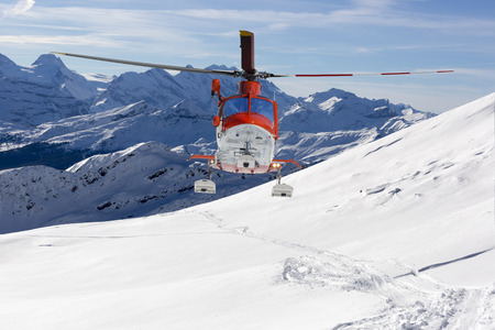 Rescue helicopter lands in snow capped mountainsの写真素材