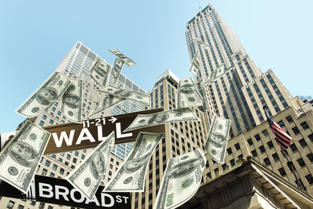 Hundred dollar bills money falling down the buildings of the Wall street. The road signs wall street corner broad street show the location.の写真素材