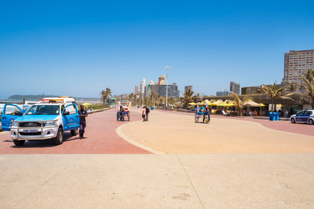 DURBAN, SOUTH AFRICA - NOVEMBER =2, 2017: People are walking on the bay of plenty promenade. The foreground shows a police car with officers.のeditorial素材