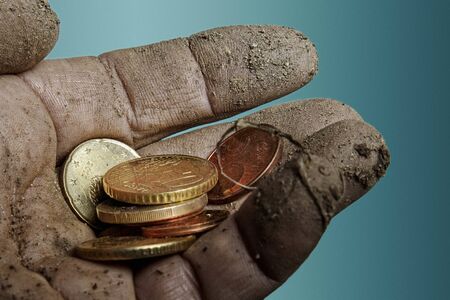 Persons dirty left hand holds some Euro coins in her palm.
