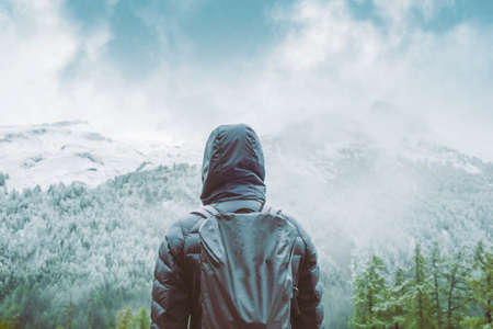 Rear view of person, standing in front of a slight snow capped mountain range.の写真素材