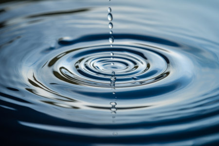 Water drop close-up with ripples and waves on blue backgroundの素材