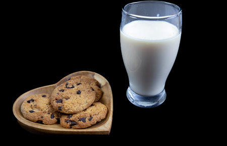 Chocolate chip cookies and a glass of milk on a black backgroundの写真素材