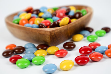 Colorful candies in wooden bowl on white background. Studio shot.の写真素材