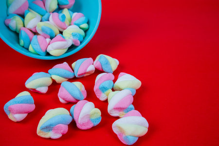 Colorful marshmallows in a blue bowl on a red backgroundの写真素材