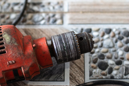 Close-up of an old electric drill on a stone floor.の写真素材