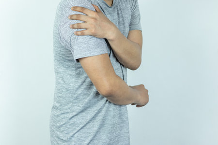Man suffering from shoulder pain on white backgroundの写真素材