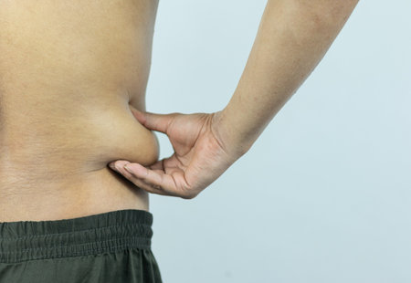 Man touching pot belly or belly fat. Close-up of body parts