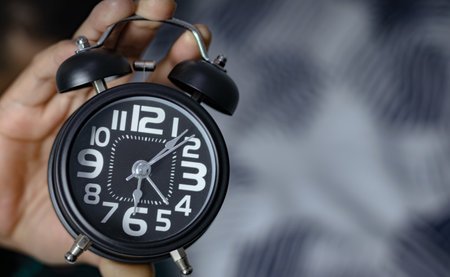Time management concept. Man hands holding Black retro alarm clock. Time to wake up for the morning routineの写真素材