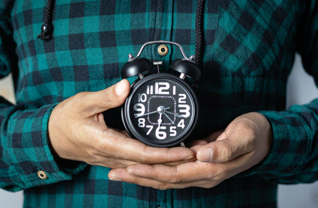 Time management concept. Man hands holding Black retro alarm clock. Time to wake up for the morning routineの写真素材