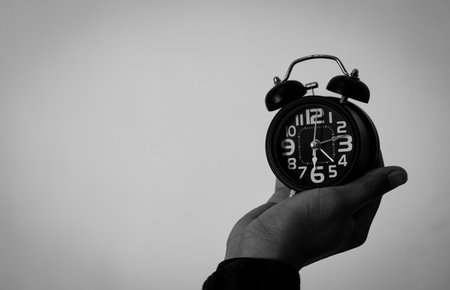 Time management concept. Man hands holding Black retro alarm clock. Time to wake up for the morning routineの写真素材