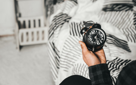 Time management concept. Man hands holding Black retro alarm clock. Time to wake up for the morning routineの写真素材
