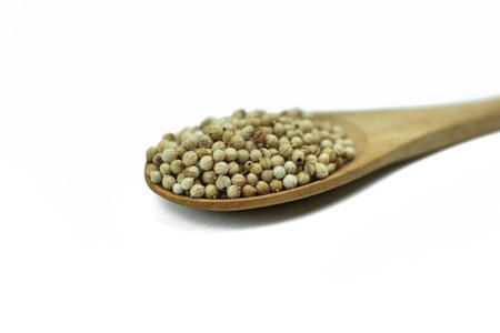 Close-up of Coriander seeds on wooden spoon isolated on white backgroundの写真素材