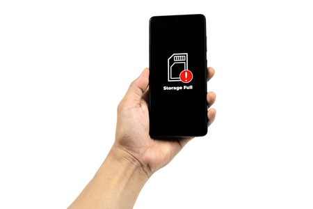 Cellular Problems Concepts. Man hand holding smart phone with full storage icon on screen isolated on white background. All screen graphics are made up.の写真素材