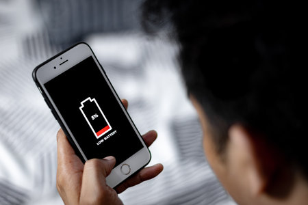 Cellular Problems and Energy Concepts. Man hand holding Smartphone with sign low battery icon on screen.の写真素材