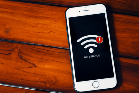 Smart phone with sign no service on screen on wooden background. Communication, cellular problem,...